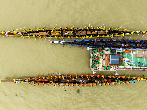 Aerial view of a traditional boat race with many rowers in long wooden boats on the river in Manikganj, Dhaka Division, Bangladesh.