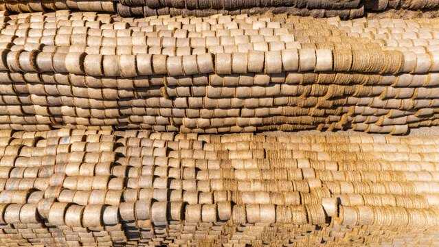 Aerial view of stacked cylindrical hay bales arranged in rows on a farm field under bright sunlight in Sabac, Vojvodina, Serbia.
