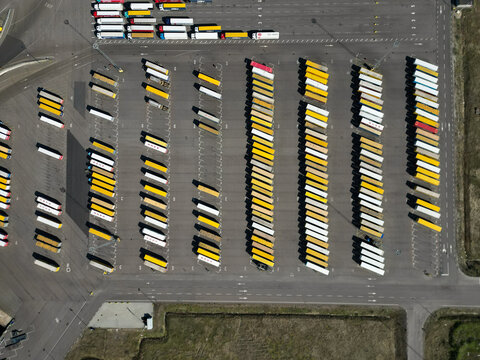 Aerial view of a large logistics center with rows of parked semi-trucks and trailers in a paved parking lot in Malmo, Skane County, Sweden.