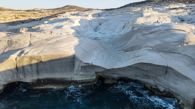 Aerial view of Sarakiniko beach featuring unique white volcanic rock formations and turquoise sea waters under clear sky in Milos, Greece.
