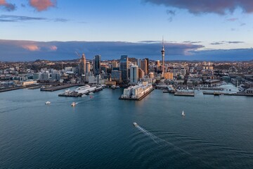 Obraz premium Scenic aerial view of the Auckland CBD skyline and Waitemata Harbour with boats cruising at sunset in Auckland, New Zealand.