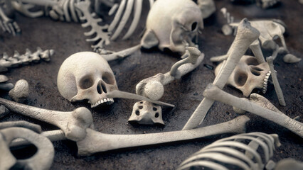 Human skeletons scattered on dark ground, with visible skulls, ribs, femurs, and gritty soil beneath dim lighting. © Piotr Adamczyk