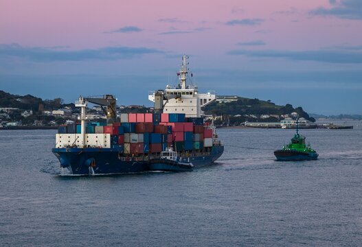 Tugboats guide a container ship navigating Waitemat? Harbour in Auckland, New Zealand, to facilitate safe maritime shipping and transport.
