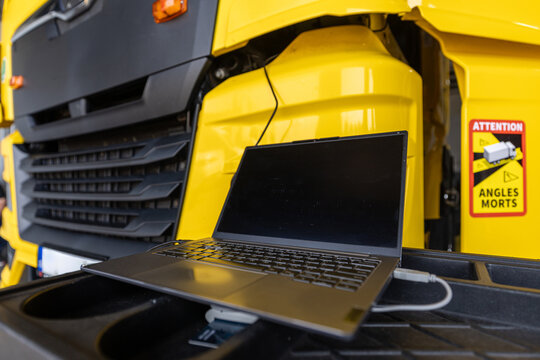 Truck service.  Diagnostic laptop connected to a modern yellow heavy duty commercial truck for maintenance and computer troubleshooting in a professional automotive repair workshop