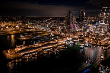 Obraz premium Stunning night view of the illuminated Auckland city skyline, harbor, and ferry terminal in Auckland Central, New Zealand.