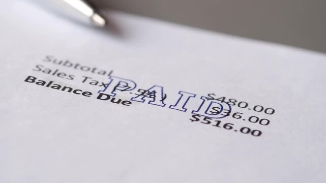 Paid stamp being applied to financial document with subtotal sales tax and balance due