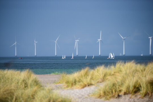 Aerial view of Amager Beachpark with wind turbines in the sea and small sailboats near the coast of Copenhagen, Denmark.