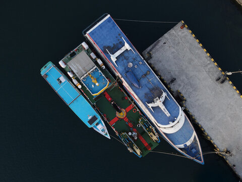 Aerial view of Waisai Harbour with passenger ferries docked at the concrete pier in the clear waters of the archipelago, Raja Ampat, Papua Barat Daya, Indonesia.