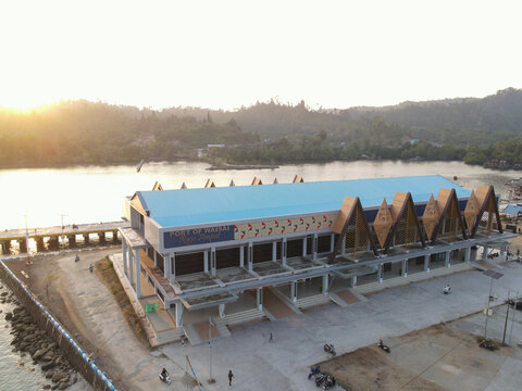 Aerial view of Waisai Harbour terminal building with its distinctive blue roof and traditional architectural elements at sunset in Raja Ampat, Papua Barat Daya, Indonesia.