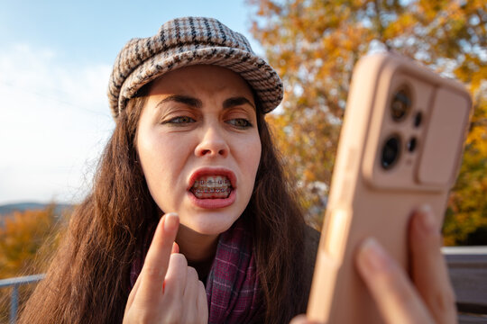 Portrait of young woman expressing anger and disbelief after receiving disturbing information on mobile phone. Communication and emotional reaction concept.
