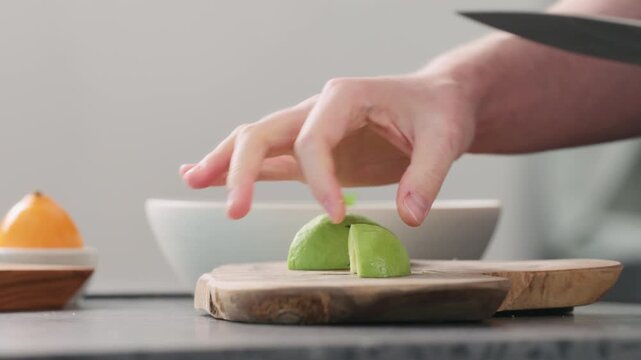 Man slicing ripe avocado on kitchen countertop side view
