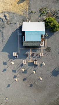Aerial view of Ada Bojana beach restaurant with straw umbrellas and wooden walkways on the sand in Ulcinj Municipality, Montenegro.