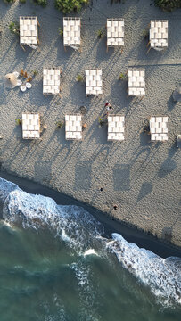 Aerial view of Ada Bojana beach with white cabanas, sandy shore, and ocean waves in Ulcinj Municipality, Montenegro.