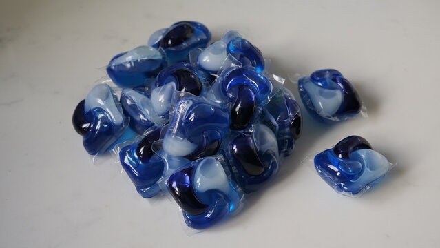 Pile of blue laundry detergent pods on a white surface