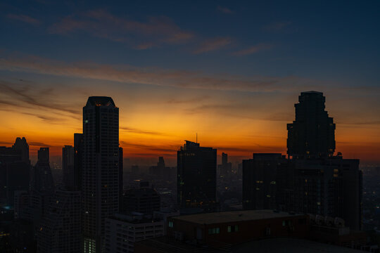 Aerial view of the North Sathorn district skyline with silhouetted skyscrapers against a vibrant sunset sky in Bangkok, Krung Thep Maha Nakho, Thailand.