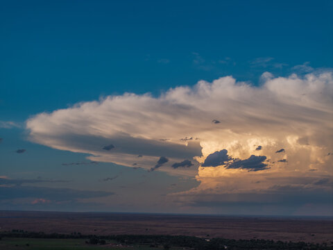 Aerial view of a large cumulonimbus cloud formation glowing in the golden light of sunset over the vast plains of Fountain, CO, United States.