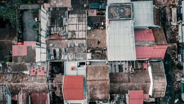 Aerial view of the dense urban rooftops of Mekarwangi featuring a mix of weathered clay tiles and corrugated metal sheets in Tanah Sareal, West Java, Indonesia.