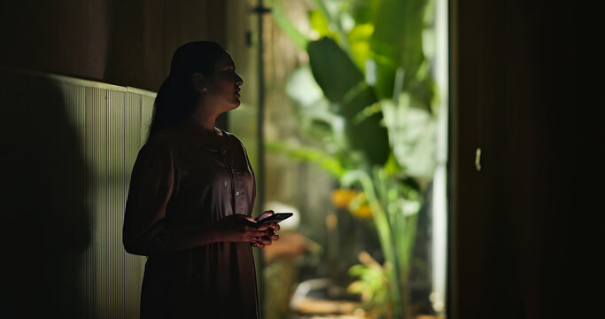Indian young adult gen z stress sad woman use mobile look screen read bad news indoor dark home. Upset tense girl hold phone check mail lost job result fail feel hurt living room place