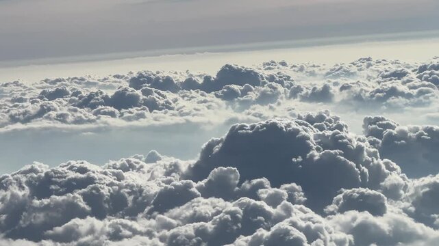 Aerial view of fluffy white cumulus clouds floating above earth seen from airplane window during travel.