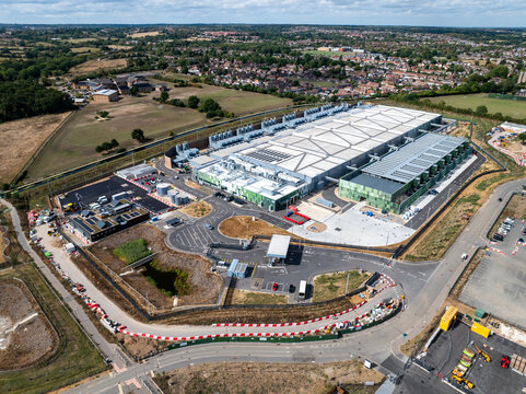 Aerial view of the Google Data Centre in Waltham Cross, featuring large industrial facilities, parking lots, and surrounding green landscape in Cheshunt, England, United Kingdom.
