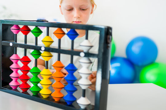 Young boy visualizing and practicing mental arithmetic with a colorful abacus, developing concentration, calculation and cognitive skills.