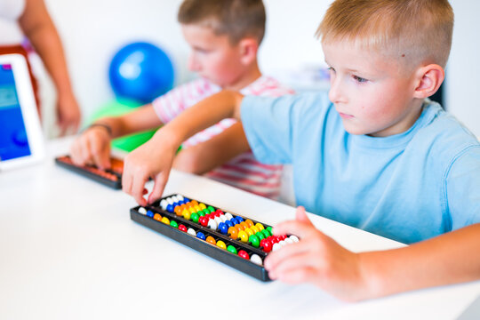 Children using abacuses to practice mental arithmetic, counting and calculation skills during a classroom lesson.