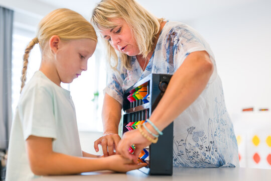 Teacher helps a young boy learn mental arithmetic and counting using a large colorful abacus during an educational lesson.
