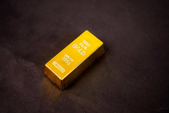 A gleaming gold bar rests on a black background.