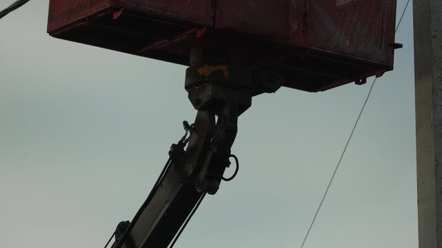 Crane lift hydraulic cherry picker basket moving against cloudy sky for industrial and construction work context