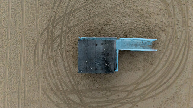 Aerial view of a lifeguard tower on the sandy beach at Venice Beach with tire tracks in the sand in Los Angeles, California, United States.