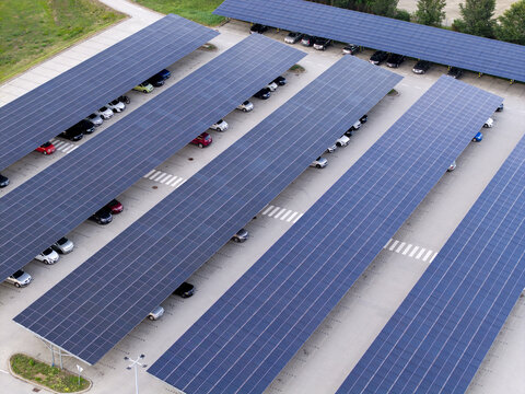 Aerial view of photovoltaic solar panels covering a large parking lot with parked cars in Poland.