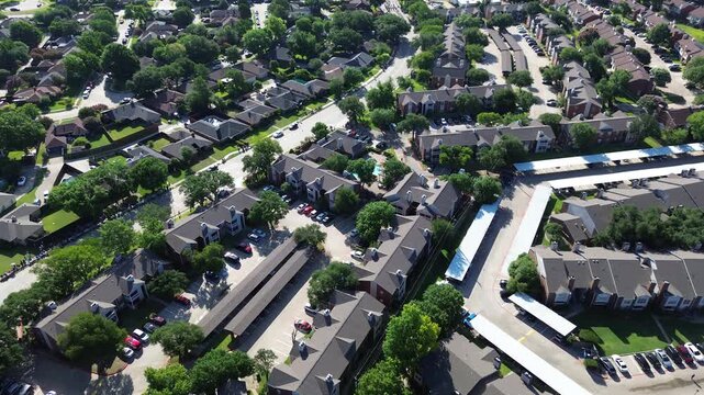 Multifamily apartment developments flank Parkway Boulevard near Mockingbird Elementary School. Extended white carport shelters, swimming pool decks, dense tree canopies grace Coppell, Texas.
