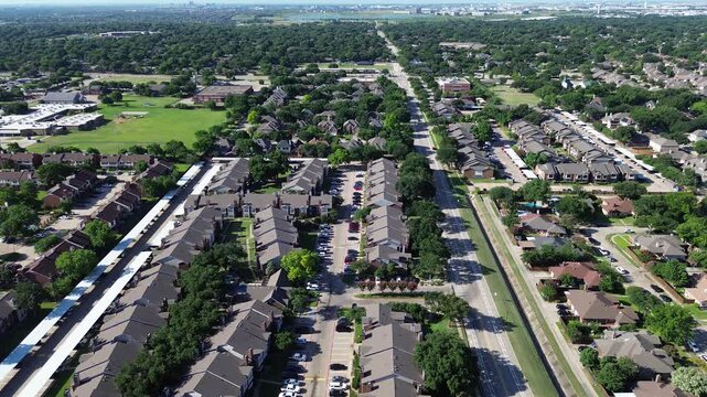 Multifamily apartment blocks flank Parkway Boulevard near Moore Road. Parallel covered vehicle carports, paved driveways, green tree canopies line residential grounds across Coppell, Texas.
