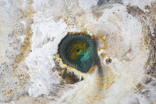 Aerial view of the vibrant Hveravellir geothermal pool showing colorful mineral deposits and steaming water in Hunabyggd, Iceland.