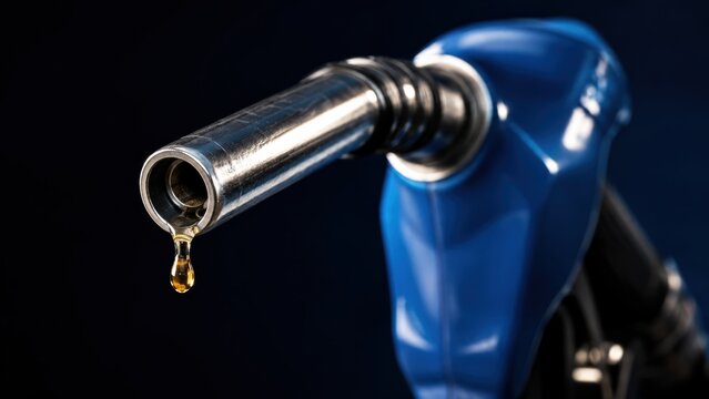 Close-up of a blue fuel pump nozzle with a fuel drop falling against a black background.