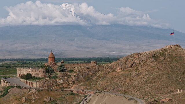 Aerial view of Khor Virap Monastery with its historic stone walls and church domes set against the backdrop of Mount Ararat under a cloudy sky, Lusarat, Ararat Province, Armenia.