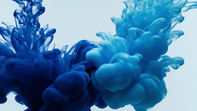 Abstract dark blue ink clouds swirling and dissolving in clear liquid against pale background