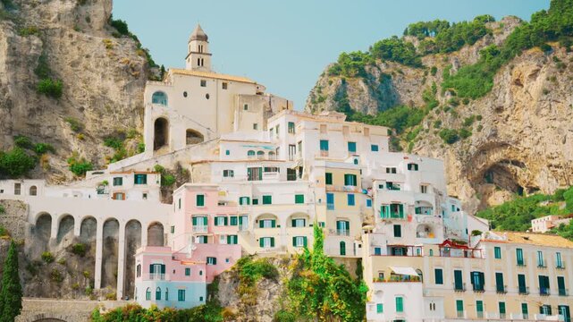 Sunlit belfry and white houses dwarfed by towering grey crags in Amalfi