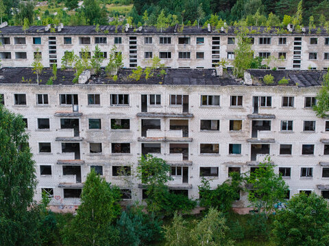 Aerial view of abandoned Soviet-era apartment buildings in the ghost town of Irbene, with decaying facades and trees growing on rooftops in Irbene, Ventspils Municipality, Latvia.