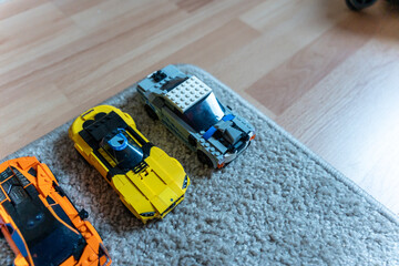 Obraz premium Warsaw, Poland - Sep 4, 2026: Row of LEGO Technic model cars in orange, yellow and blue on a gray rug