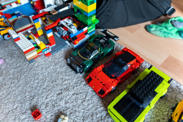 Obraz premium Warsaw, Poland - Sep 4, 2026: Assorted LEGO building blocks and mini figures scattered on a gray rug beside toy cars