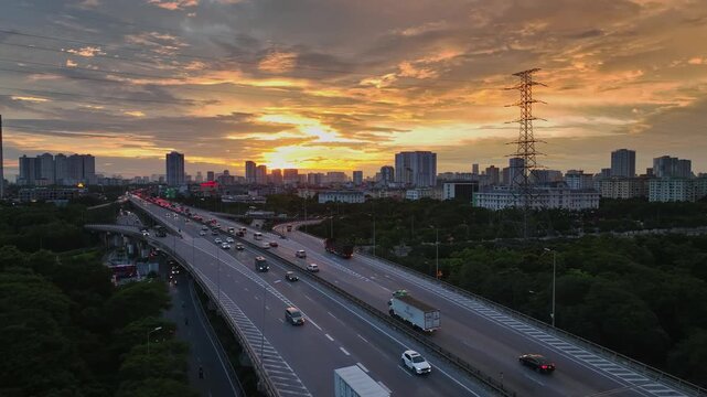 Aerial view of Hanoi's Ring Road 3 passing through Yen So, with flowing traffic, elevated highways, city buildings, greenery, and a dramatic sunset sky.