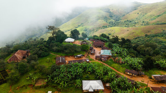 Aerial view of Obudu Mountain Resort featuring rustic buildings nestled among lush green hills, banana trees, and misty mountain slopes in Obudu, Cross River, Nigeria.