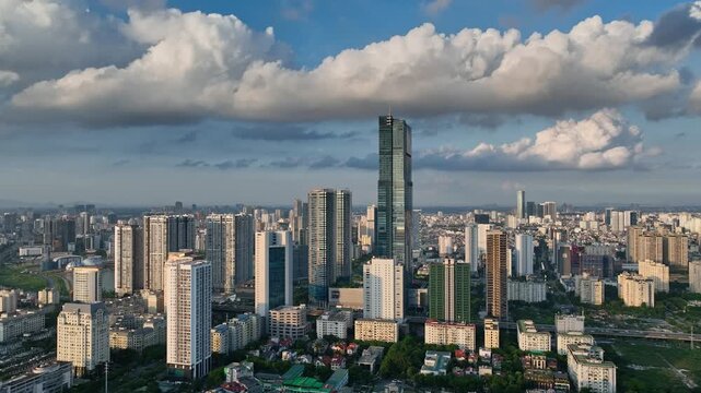 Aerial cityscape view of modern Hanoi near the Me Tri and Pham Hung intersection, featuring high-rise buildings, dense urban development, and dramatic clouds.