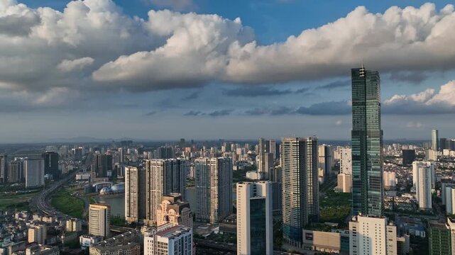 Panoramic urban skyline of Hanoi viewed from above, featuring dense high-rise buildings, Landmark 72 tower, green spaces, and dramatic clouds near Me Tri and Pham Hung.