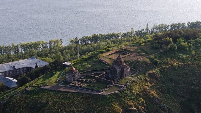 Aerial view of the historic Sevanavank Monastery complex situated on a grassy peninsula overlooking the vast blue waters of Lake Sevan in Sevan, Gegharkunik Province, Armenia.