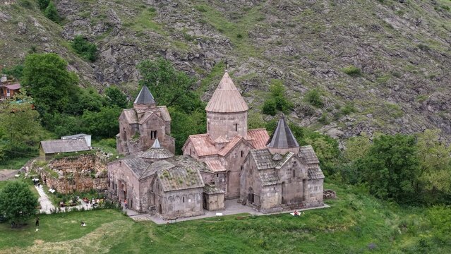Aerial view of Goshavanq Monastery featuring ancient stone churches with conical domes nestled in a lush green valley surrounded by rocky hills in Gosh, Tavush Province, Armenia.