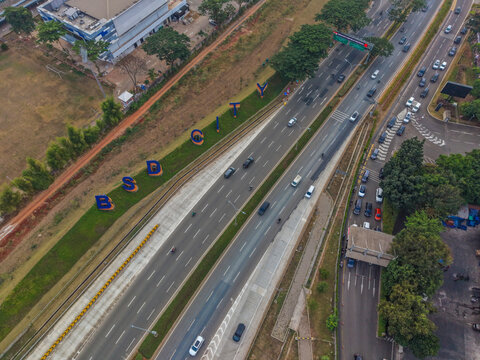 Aerial view of the BSD City landmark sign alongside a multi-lane highway with moving vehicles and surrounding greenery in Serpong Sub-District, Banten, Indonesia.