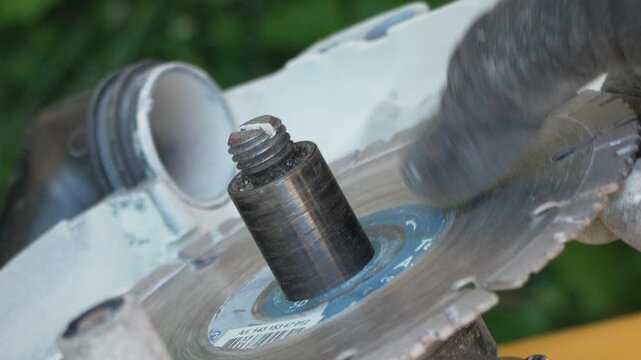 Diamond blade installation on a masonry saw spindle outdoors. Extreme close-up shot.