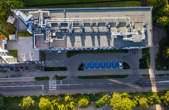 Aerial view of Apartaments Collegia featuring a flat roof with ventilation systems, a parking lot with blue accessible spaces, and a road in Gdansk, Pomeranian Voivodeship, Poland.